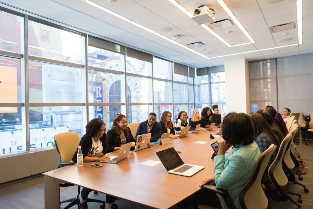 Women collaborating around a table with laptops in a bright workspace.