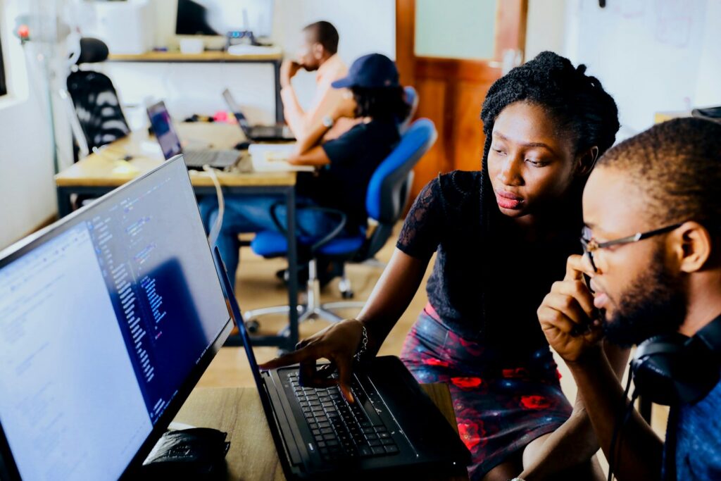 Two learners working together at a laptop in a training space.